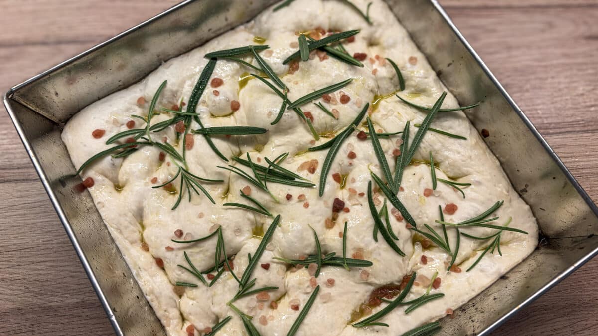 Surowa focaccia z głębokimi dołkami, świeżym rozmarynem i gruboziarnistą solą himalajską