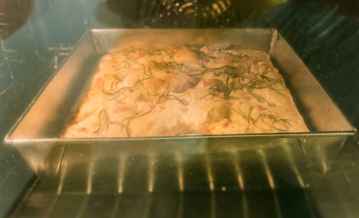 Focaccia z rozmarynem piekąca się na środkowej półce piekarnika