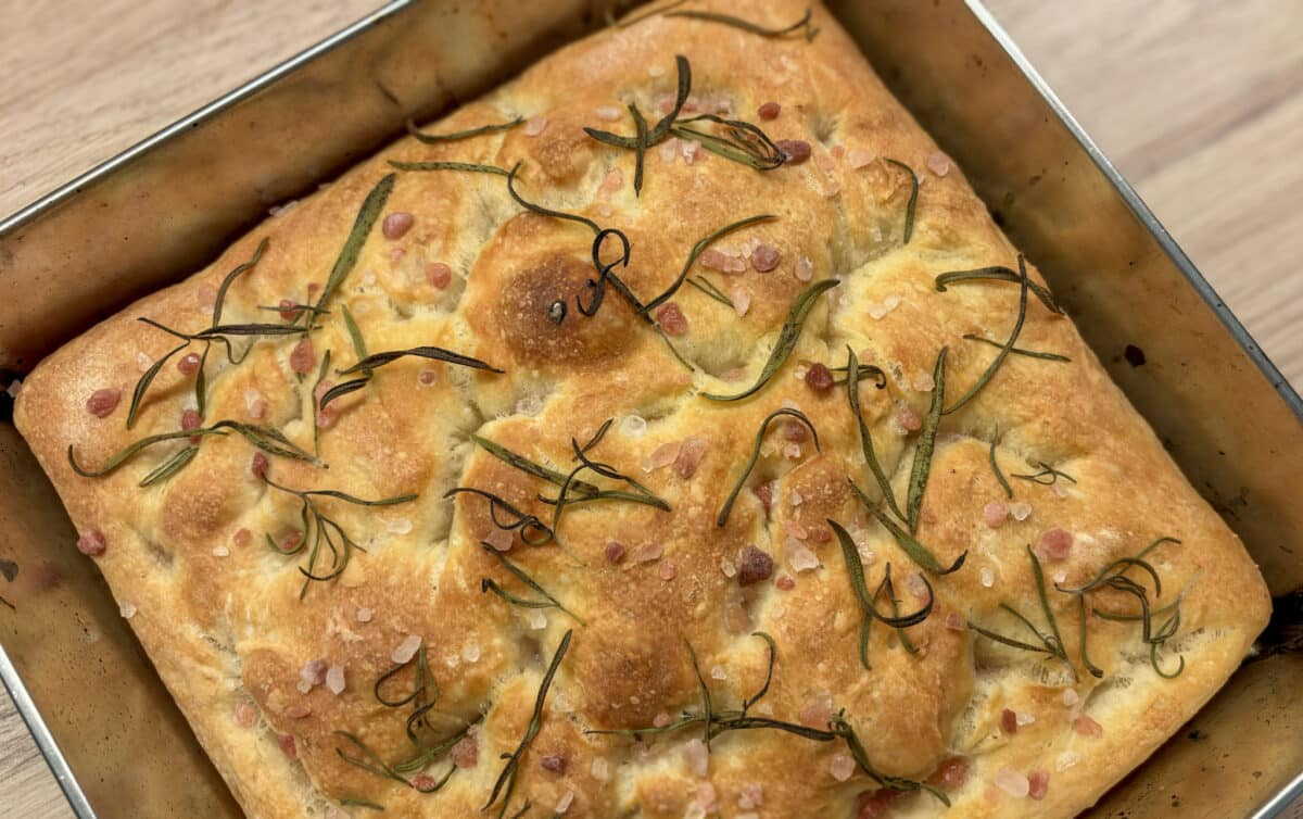 Złocista focaccia z rozmarynem i gruboziarnistą solą w metalowej blasze