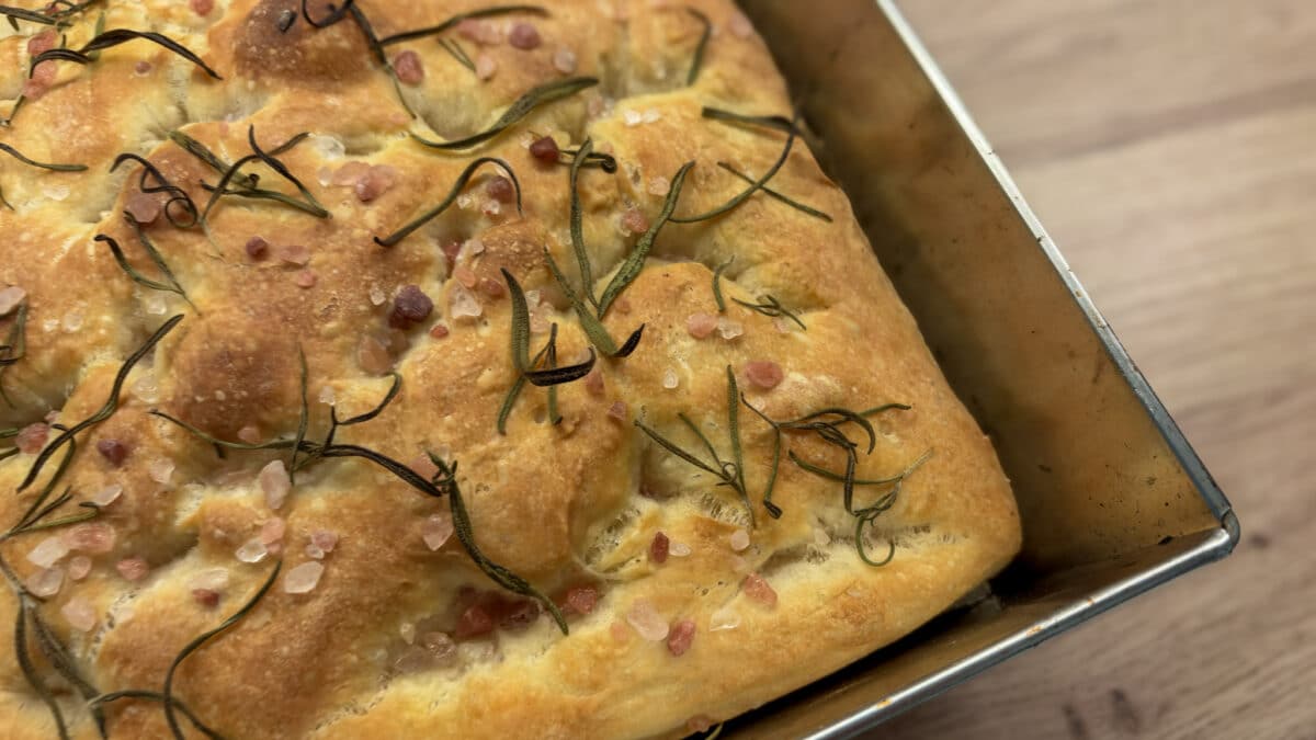 Złocista focaccia z rozmarynem i gruboziarnistą solą w metalowej blasze