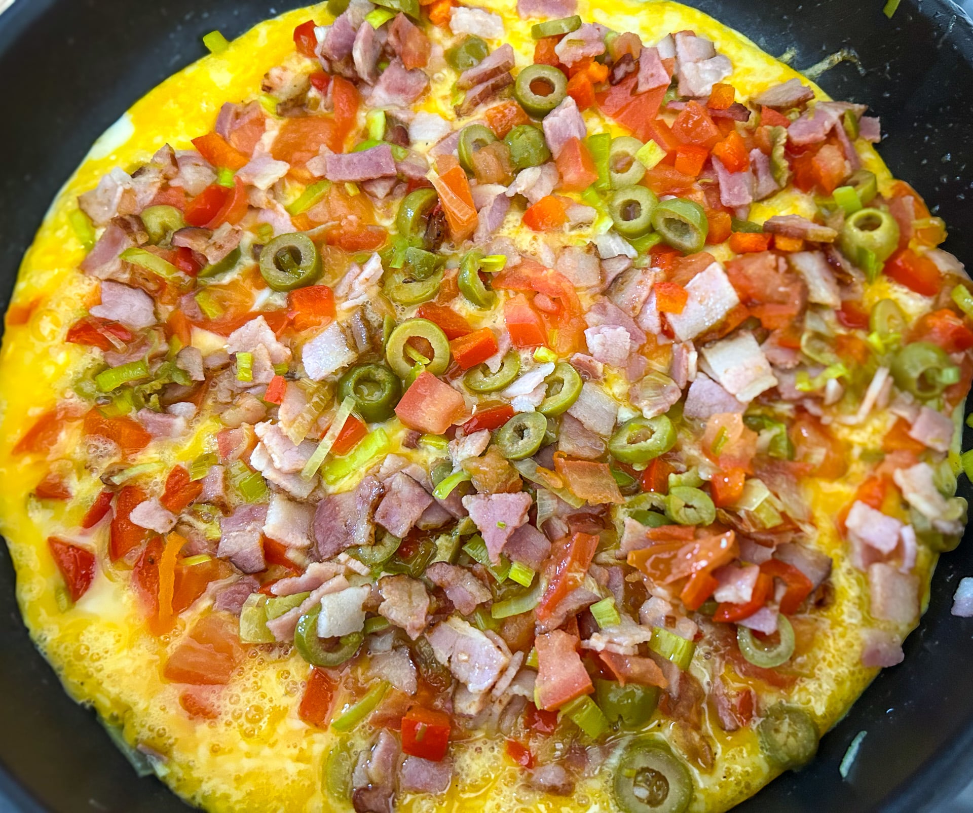a pan of omelette with vegetables and meat