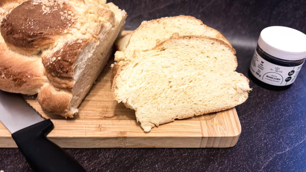 Przekrojona chałka drożdżowa z kruszonką, kromki na desce i pasta waniliowa Pi‑NUTS.