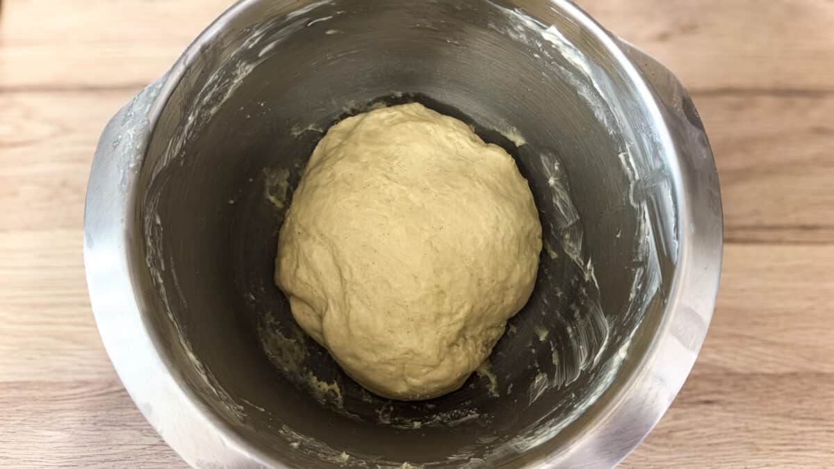 Wyrobione ciasto drożdżowe w metalowej misie przed rozpoczęciem wyrastania.