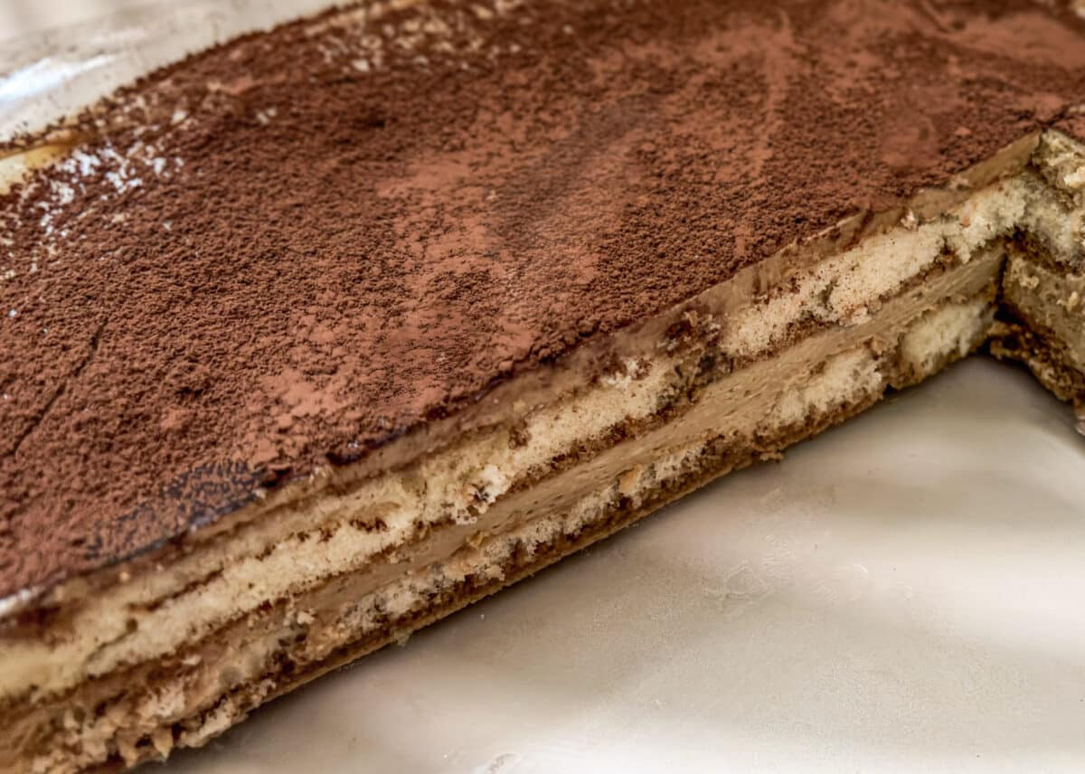 Tiramisu pistacjowe – kremowy włoski deser bez pieczenia 6 Przekrój tiramisu pistacjowego z kremem mascarpone, biszkoptami nasączonymi kawą i kakao