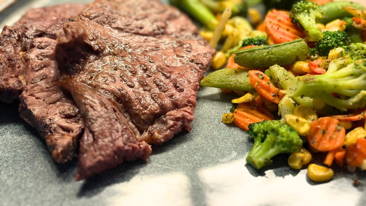 Zbliżenie upieczonego steka obok brokułów, marchewki i zielonych strąków