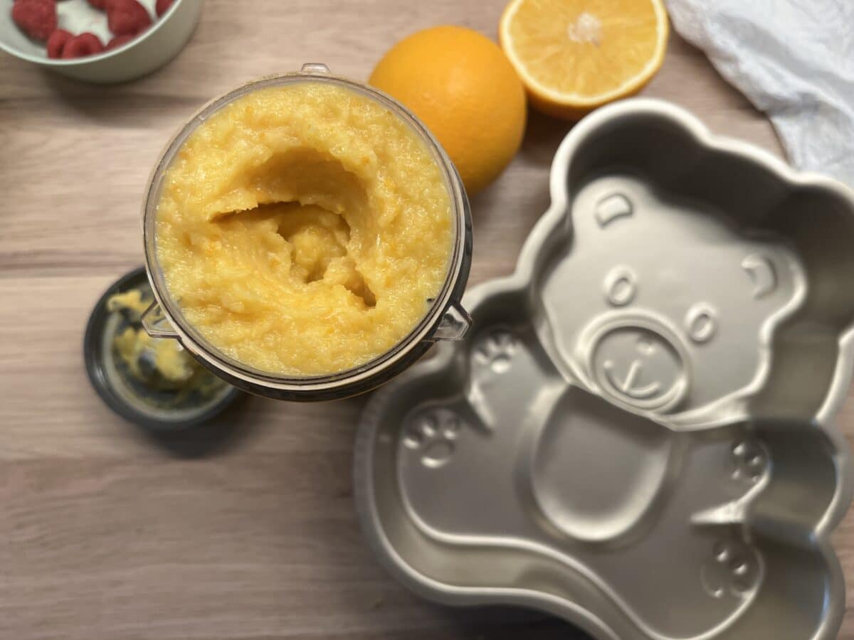 Puree z gotowanych pomarańczy w blenderze obok pustej formy do pieczenia w kształcie misia i pomarańczy