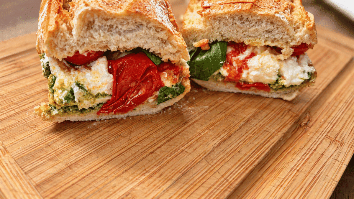 Kanapka w bagietce z burratą, pesto, pomidorkami i bazylią